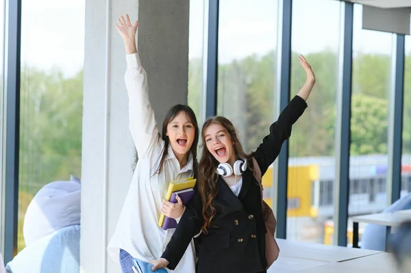 Two Young Women Book Chatting While Standing College Corridor University — Stock Photo, Image