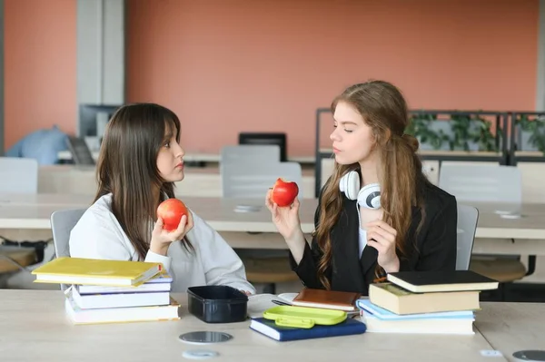 Dos Estudiantes Sonrientes Felices Están Sentadas Comiendo Manzanas Estudiando Preparándose —  Fotos de Stock