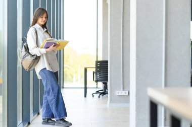 Okulda kitap ve sırt çantasıyla duran liseli kız.