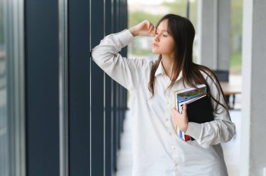 Okuldaki bir kızın portresi. O, kitapları elinde tutuyor. Eğitim kavramı