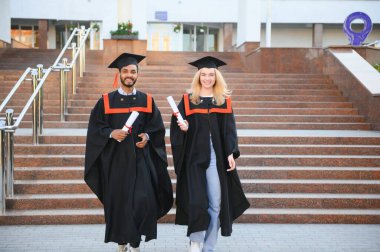 Eğitim, mezuniyet ve halk konsepti. Havan ve bekarlığa veda elbisesi giyen mutlu uluslararası öğrenciler.