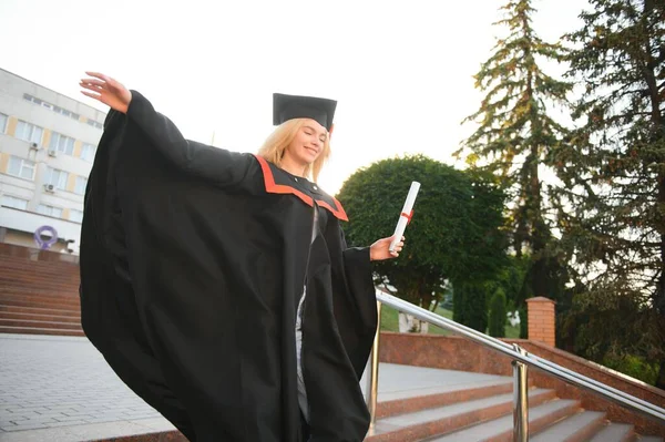 대학원생 소녀가 있습니다 모르타르 가운을 곱슬머리에 졸업장을 — 스톡 사진