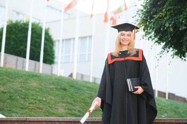 Üniversitenin arka planında genç bir bayan mezun.