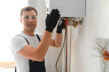 Gas engineer checking and cleaning a boiler during the inspection at home.