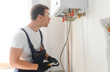 Gas engineer checking and cleaning a boiler during the inspection at home.