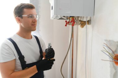 Professional boiler service: qualified technician checking a natural gas boiler at home.