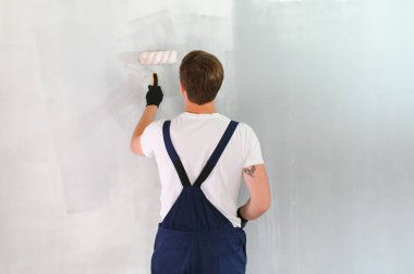 İşçi ressam bir duvar boyuyor. Profesyonel inşaatçı tamirat yapar.