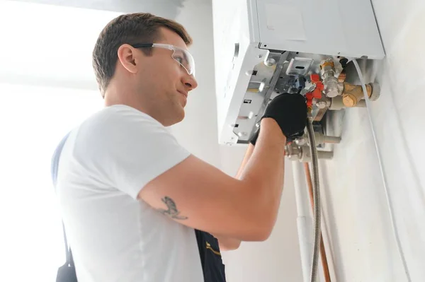 Professional boiler service: qualified technician checking a natural gas boiler at home.