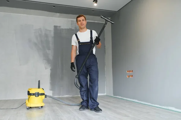 作業員は床を修理した後 部屋を掃除します 掃除機で改装後のアパート — ストック写真