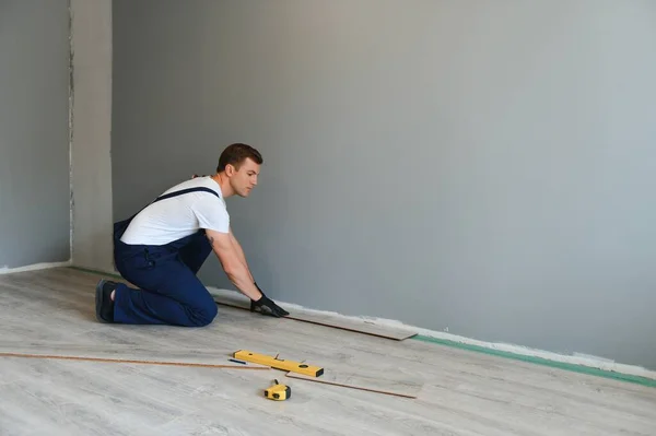 新しい積層木製の床を設置する男 — ストック写真