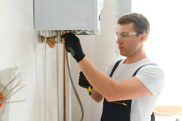 Professional boiler service: qualified technician checking a natural gas boiler at home.