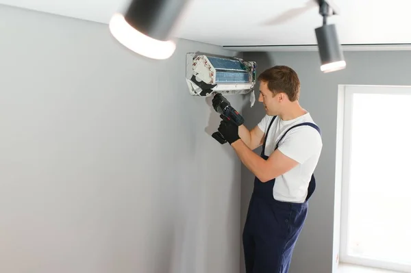 壁にエアコンを修理する技術者 — ストック写真
