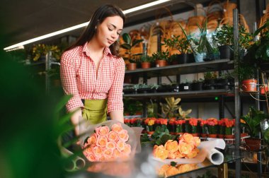 Genç güzel kadın çiçekçi çiçekçide buket çiçek yapıyor..