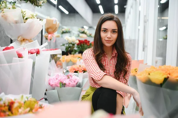 Beautiful florist at flower shop. Woman working in floral shop with copy space. Successful florist smiling.