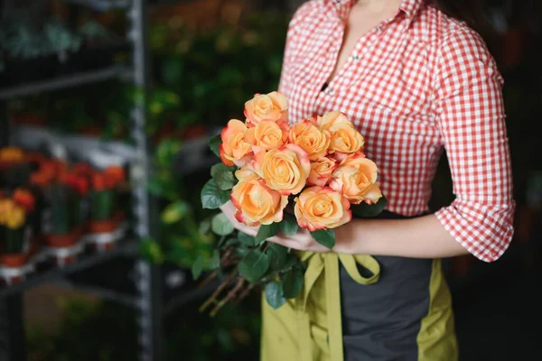 Young beautiful woman florist make bouquet of flowers at flower shop.
