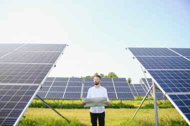 Solar power plant. Man standing near solar panels. Renewable energy