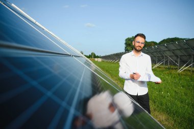 Young architect standing by solar panels.