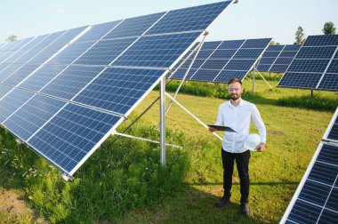 Solar power plant. Man standing near solar panels. Renewable energy