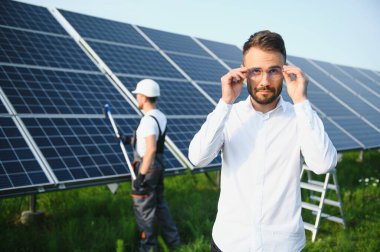 Fotovoltaik panellerin arka planında erkek işçi güneş enerjisi santrali