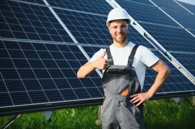 Fotovoltaik panellerin arka planında erkek işçi güneş enerjisi santrali