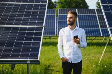 Young architect standing by solar panels.