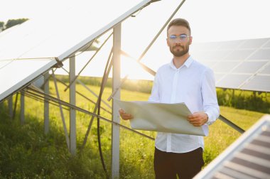 Young architect standing by solar panels.