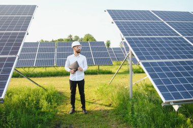 Fotovoltaik panellerin arka planında erkek işçi güneş enerjisi santrali