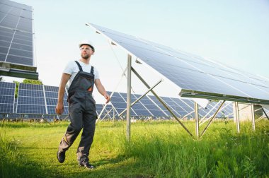 Fotovoltaik panellerin arka planında erkek işçi güneş enerjisi santrali