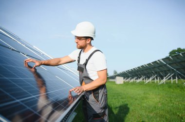 Fotovoltaik panellerin arka planında erkek işçi güneş enerjisi santrali