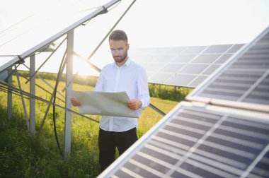 Young architect standing by solar panels.
