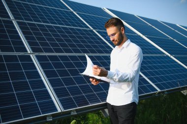 Fotovoltaik panellerin arka planında erkek işçi güneş enerjisi santrali