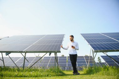 Fotovoltaik panellerin arka planında erkek işçi güneş enerjisi santrali
