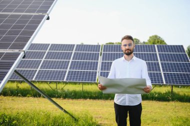 Fotovoltaik panellerin arka planında erkek işçi güneş enerjisi santrali