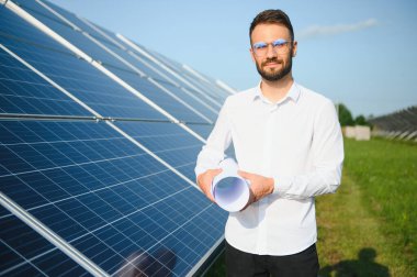 Solar power plant. Man standing near solar panels. Renewable energy