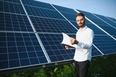 Young architect standing by solar panels.