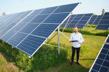 Fotovoltaik panellerin arka planında erkek işçi güneş enerjisi santrali