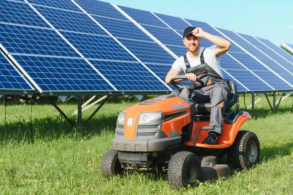 Mężczyzna Jeździ Kosiarką Koło Paneli Słonecznych Pojęcie Energii Słonecznej — Zdjęcie stockowe