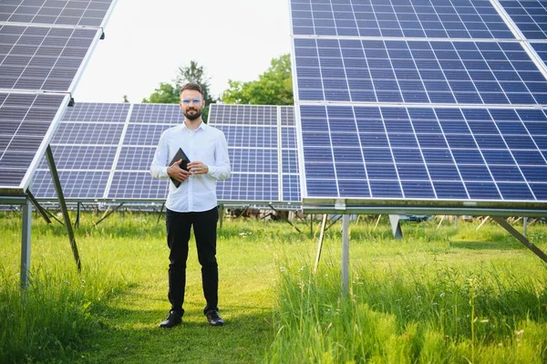 Stock image Male worker solar power plant with a tablet on a background of photovoltaic panels