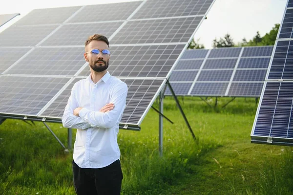 Fotovoltaik panellerin arka planında erkek işçi güneş enerjisi santrali