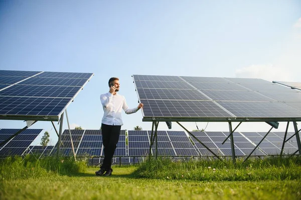 田舎の晴れた日に太陽光発電パネルの近くに立つ白いシャツの男 — ストック写真