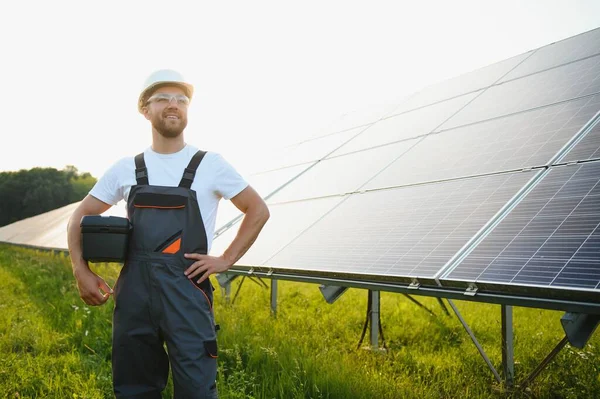 Fotovoltaik panellerin arka planında erkek işçi güneş enerjisi santrali