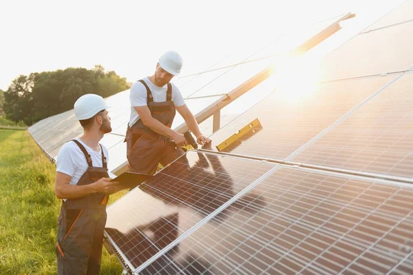 Güneş enerjisi santralinde kontrol ve bakım üzerinde çalışan mühendislik ekibi güneşli bir günde çatıya güneş panelleri kuran güneş teknisyeni.