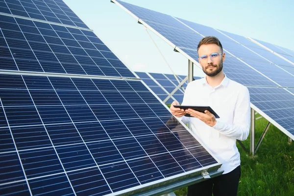 Male worker solar power plant with a tablet on a background of photovoltaic panels