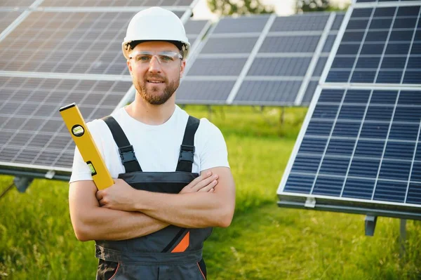 Fotovoltaik panellerin arka planında erkek işçi güneş enerjisi santrali