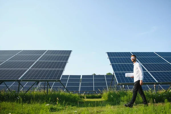 代替エネルギーを生産する太陽光パネルに対して立っている積極的なひげそりの男性投資家 — ストック写真