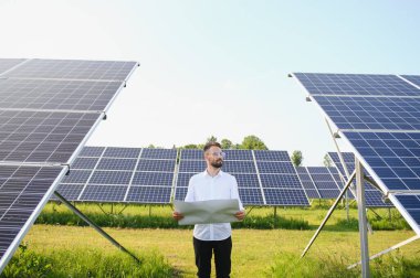 Fotovoltaik panellerin arka planında erkek işçi güneş enerjisi santrali