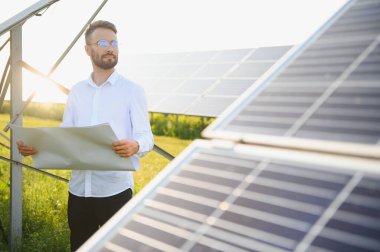 Fotovoltaik panellerin arka planında erkek işçi güneş enerjisi santrali
