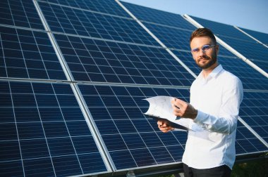 Solar power plant. Man standing near solar panels. Renewable energy