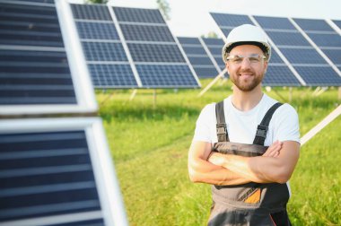 Fotovoltaik panellerin arka planında erkek işçi güneş enerjisi santrali