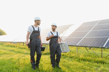 Güneş enerjisi santralinde kontrol ve bakım üzerinde çalışan mühendislik ekibi güneşli bir günde çatıya güneş panelleri kuran güneş teknisyeni.